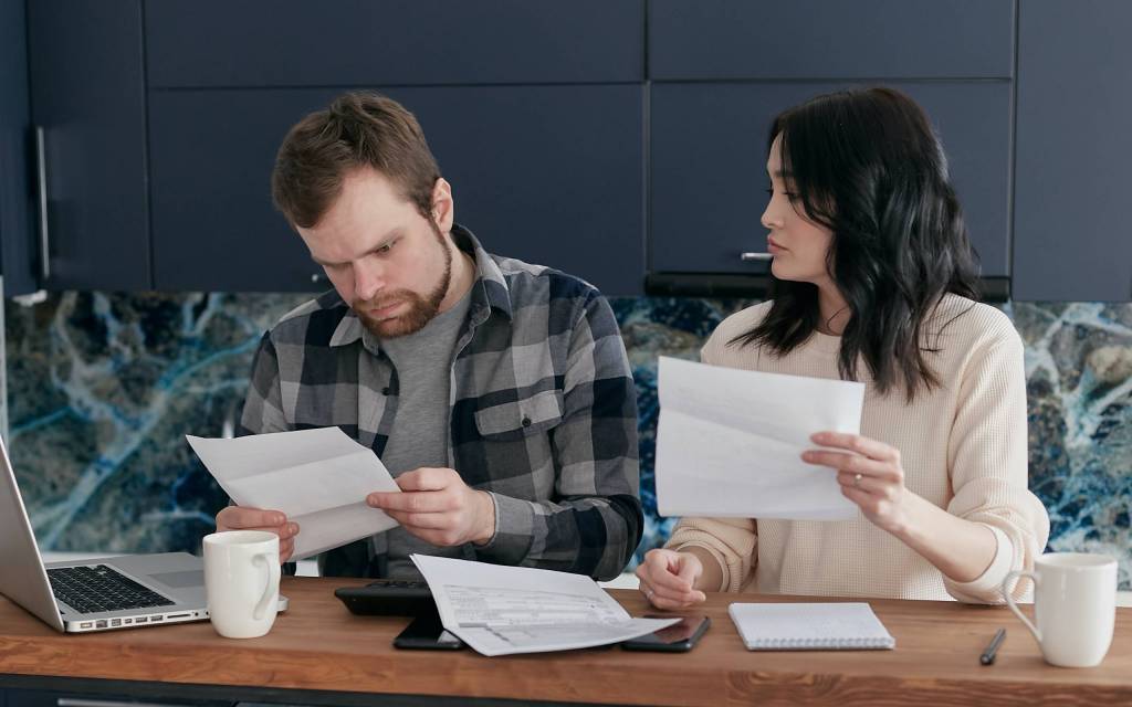 Hombre y mujer miran desconcertados un documento generado con la emisión de factura