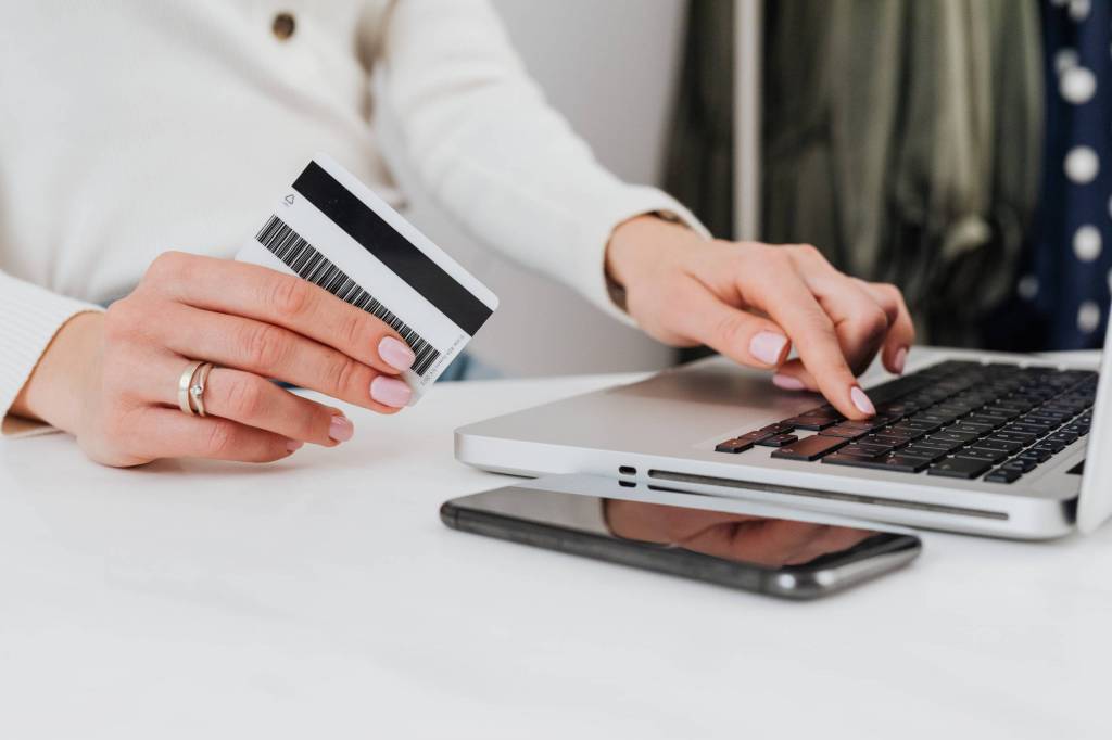Mano de mujer frente a una computadora consultando su estado de cuenta de tarjeta de crédito