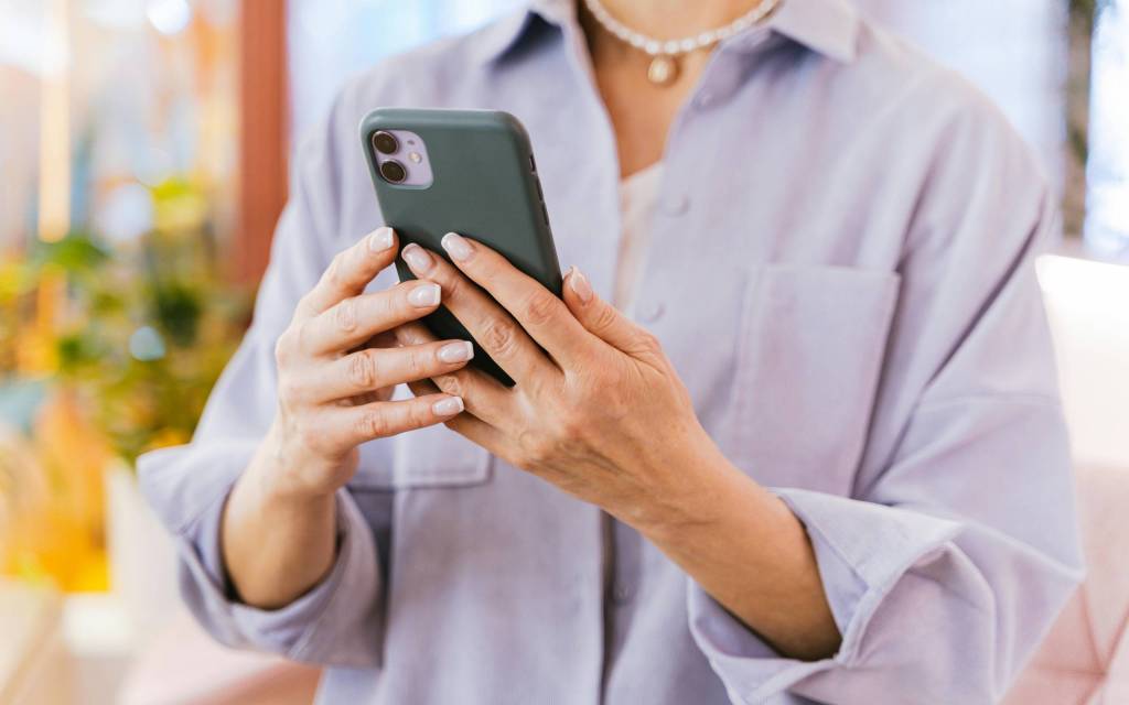 Manos con un teléfono utilizando canales de comunicación en una empresa