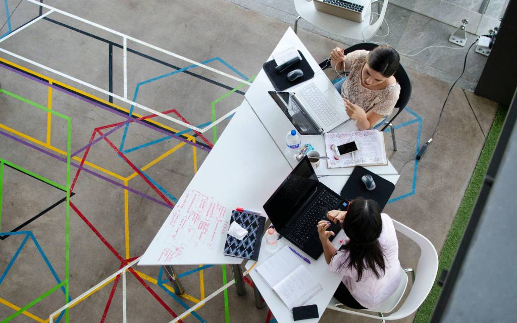 Dos mujeres conversan mientras utilizan herramientas de inteligencia artificial en las empresas